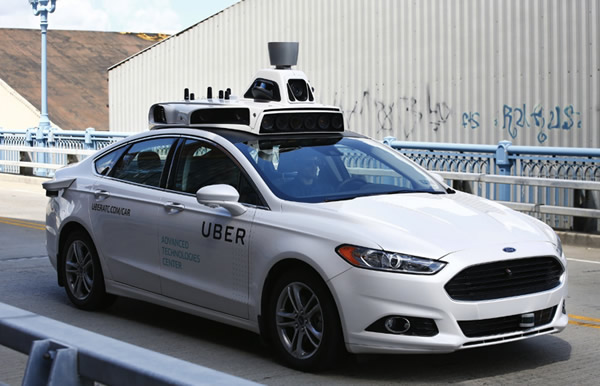 The Uber driverless car with engineer riding shotgun.